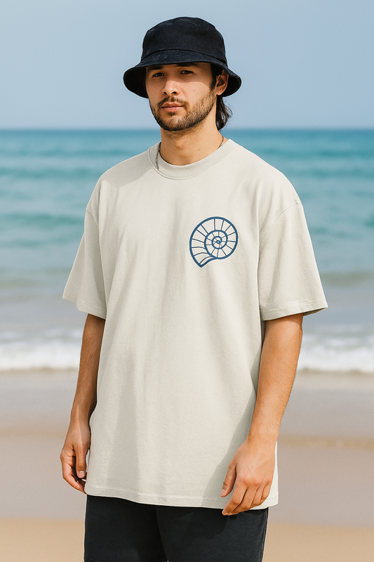 Man wearing a beige t-shirt with a logo on a beach