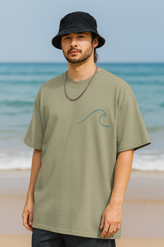 Man wearing a green t-shirt with a wave design on a beach