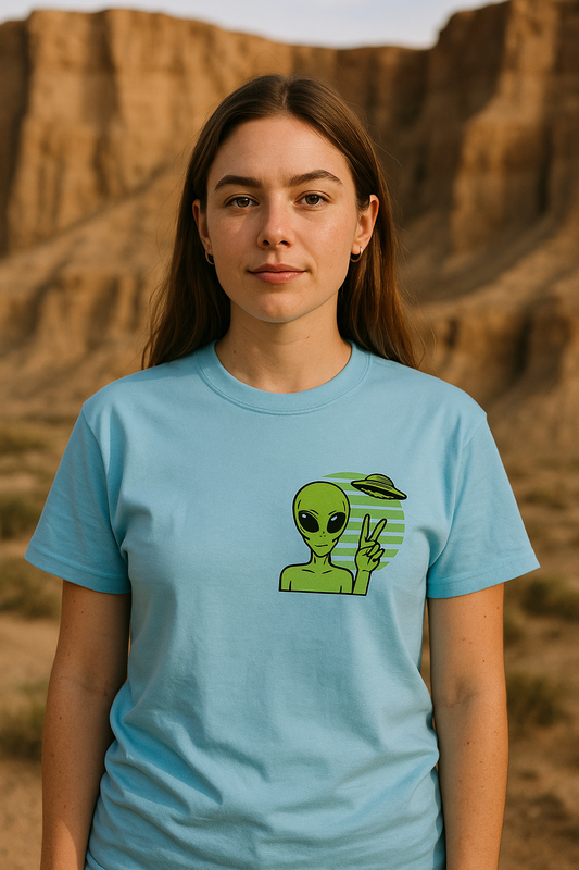 Person wearing a light blue t-shirt with an alien graphic in a desert setting