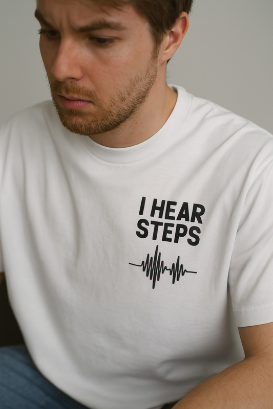 Man wearing a white t-shirt with 'I Hear Steps' text design. - escape from tarkov inspired merch