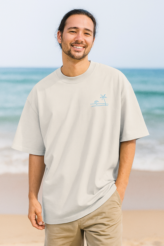 Man wearing a beige t-shirt with a palm tree design on a beach